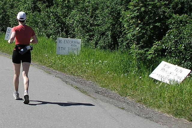 P6190037.JPG - Joyce passing the "Top 10 Reasons to Run a Marathon" signs.