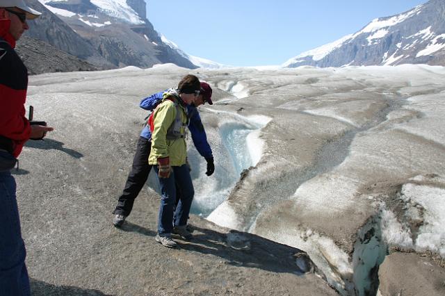 IMG_2899.JPG - Joyce peering into a sink hole/pool on the Athabasca Glacier.  Always walk on the glacier with a guide or you risk falling into one of these.